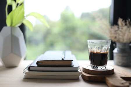 Diary notebook and coffee cup in on wooden table with window viewの写真素材