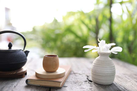 bamboo cup and metal teapot with brown notebook on wooden tableの写真素材