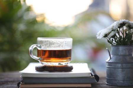 Tea cup glass and a stainless vase of white chrysanthemum flower with old bookの写真素材