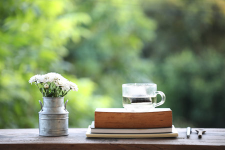 Tea cup glass and a vase of white chrysanthemum flower with old bookの写真素材