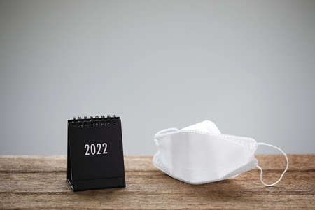 small black calendar and mask on brown desk