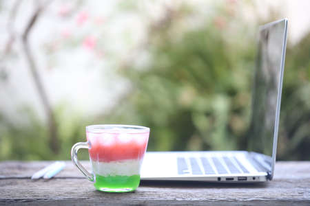 Glass of mixed juice and laptopの写真素材