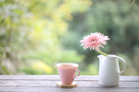 Pink cup and pink gerbera flower on wooden tableの写真素材