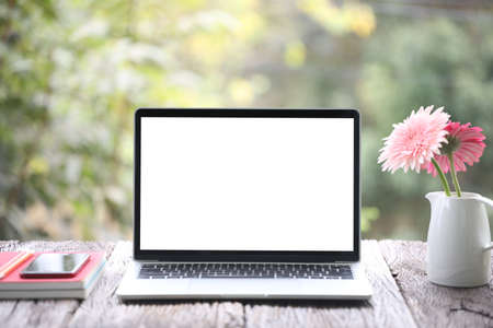 Laptop and notebooks and flower on wooden tableの写真素材
