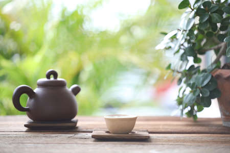 Earthenware tea pot and tea cup and plant pot on wooden tableの写真素材