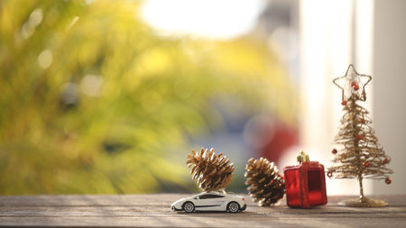 pine cones on miniature car and Christmas tree decorations on wooden table with nature outdoor viewの写真素材