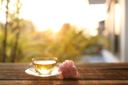 tea glass cup and pink roses head under sunlight on wooden tableの写真素材
