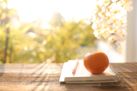 Orange and notebook diary on wooden tableの写真素材