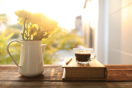 coffee glass cup with Chrysanthemum flowers and thick book on wooden table at outdoorの写真素材