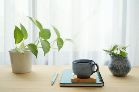 Blue coffee cup and white flower in a blue vase and notebooks and plant potの写真素材