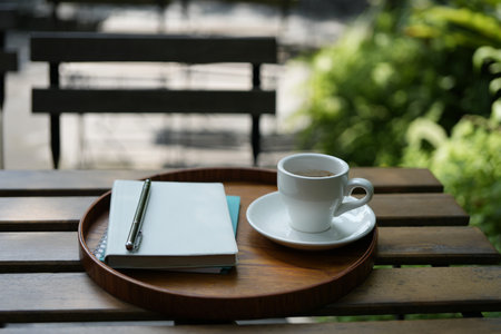 White coffee cup on wooden table with notebooks on wooden trayの写真素材