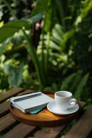 White coffee cup on wooden table with notebooks on wooden trayの写真素材
