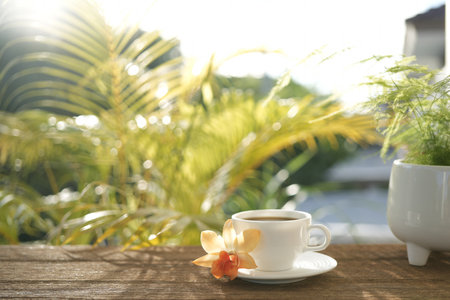 Coffee cup and orchid flower on table at balconyの写真素材