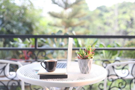 Laptop side view and coffee cup with notebooks on white table outdoor