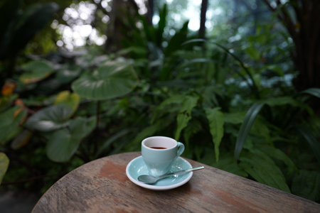 Espresso cup on weathered brown wooden table with green lush backgroundの写真素材