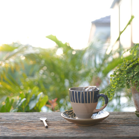 Vintage earthenware tea cup with plant pot on wooden table at balcony outdoor, slow lifeの写真素材