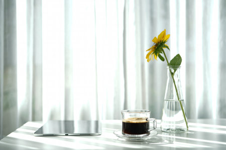 Coffee in a glass cup and tablet with sunflower on white table minimalist interiorの写真素材