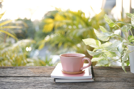Pink cup and pink pen and notebook on weathered blue wooden table pastel tones, cozy work spaceの写真素材