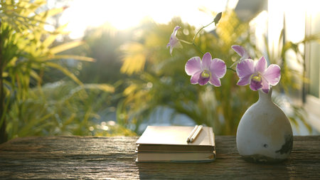 old notebook and vase of pink orchid flowers, cozy outdoor gardenの写真素材