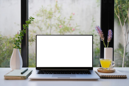 Laptop with white screen and purple flower, cozy indoor work spaceの写真素材
