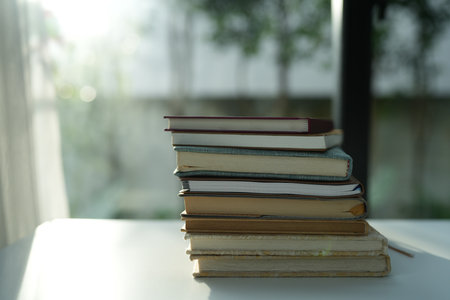 Stack of Old books on white desk by the window