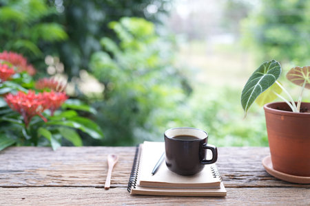 Black coffee cup and brown notebook on rustic wood tableの写真素材