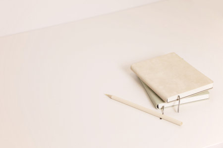 Beige and green notebooks and color pencil on minimal deskの写真素材