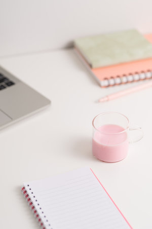 Strawberry milk in a glass cup and notebooks on white tableの写真素材