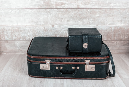 A stack of two old vintage black leather suitcase on a wooden background.の写真素材