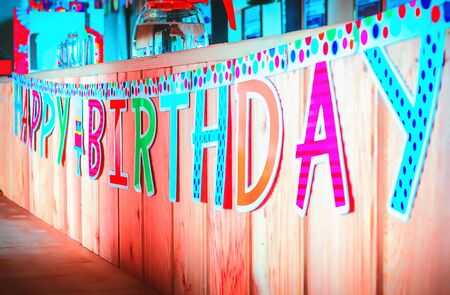 Motley Happy Birthday banner hanging on a wooden background. Selective focus.の写真素材