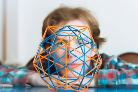 Coloured three-dimensional model of geometric solid against the background of the young man's face...