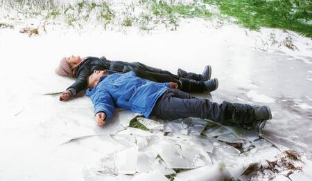 Happy cheerful young couple guy and girl  lying on the ice snow. Having fun in winter holiday....