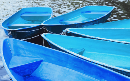 Group of tied blue and turquoise recreation rowing boats on the water closeup. Soft selective focus.
