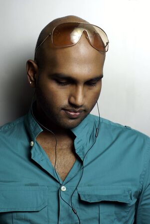 Indian man wearing earphones and green shirt  looking downの写真素材