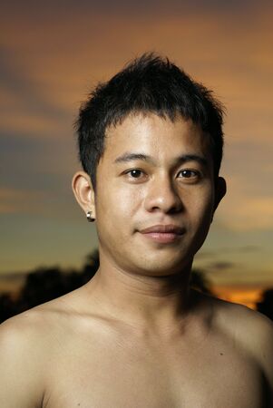 Happy asian man outdoors at twilightの写真素材