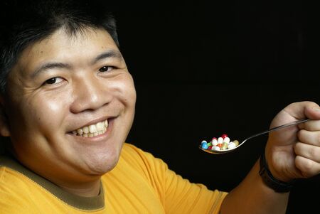 Happy man with spoon of pillsの写真素材