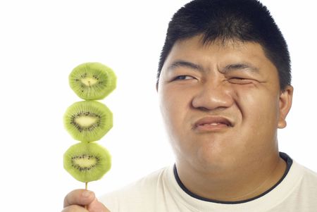 Asian man unhappy about green kiwi fruitの写真素材