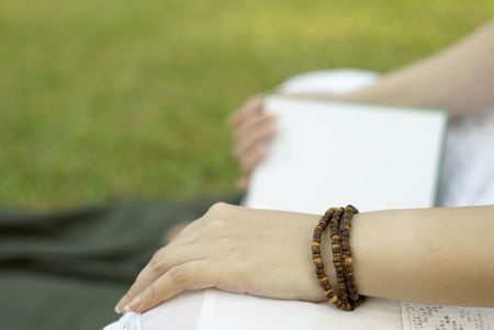 Reading book outdoors with green grass backgroundの写真素材
