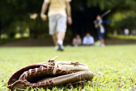 People playing softball outdoors with focus on catcher's glove on grassの写真素材
