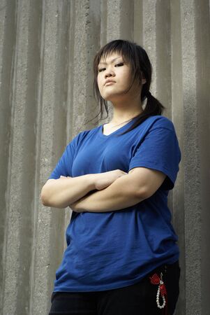 Rebellious asian teen girl leaning against wallの写真素材