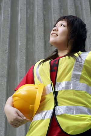 Asian female construction contractor lady looking up with concrete wallの写真素材