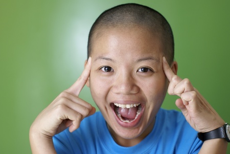 Happy asian girl point at bald head with fingersの写真素材