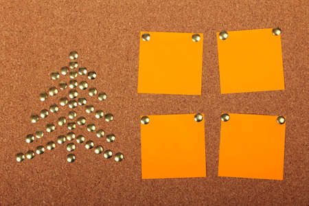 Thumb tacks in shape of Christmas tree on cork board