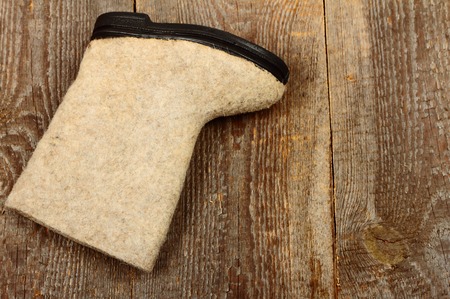 Russian traditional winter felt boot valenki on wooden background. Stock photo