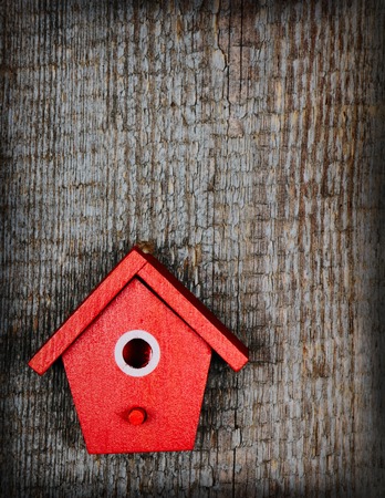 One birdhouse painted with red and white colors on old wooden backgroundの写真素材