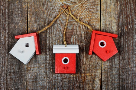Three birdhouses painted with red and white colors on old wooden backgroundの写真素材