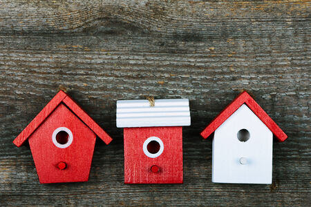 Three birdhouses painted with red and white colors on old wooden backgroundの写真素材