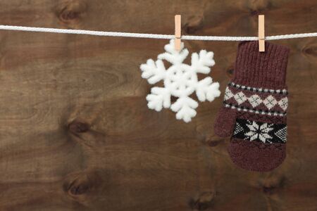 Mitten with snowflake hanging on the clothesline on brown wooden backgroundの写真素材