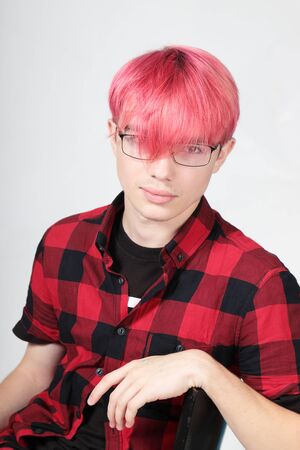 Portrait of a teenage boy with bright colored hair on gray backgroundの写真素材