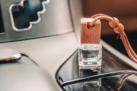 Car air perfume freshener bottle inside the car with part of car dashboard. Little glass bottle with wooden lid and aromatic liquid.の写真素材